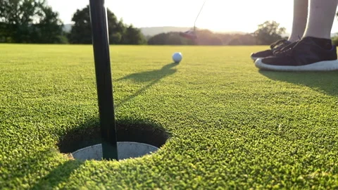 Missing the hole on a golf green. A young player putts the ball to hard  Stock Footage 162402483