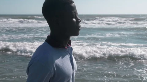 Missing mother Africa.pensive lonely black migrant walking on shore at sunset Vidéo 96337654