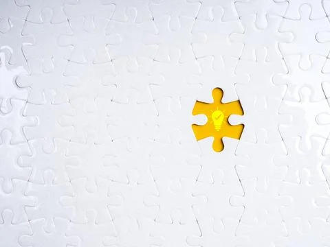 Missing puzzle piece with glowing light bulb icon on yellow background symb.. Stock Photos