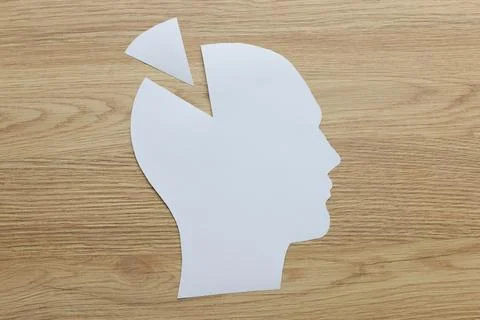 Missing triangular piece of paper head shape on wooden table 스톡 사진