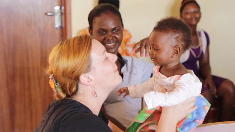 A missionary worker is lovingly cuddling and playing with a Ugandan child. 스톡 동영상 96916614