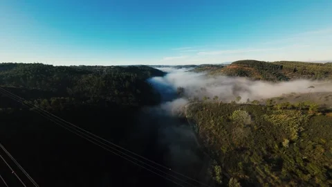 Mist curls over forested hills under clear blue sky at Castelo de Bode Stock Footage 342272864