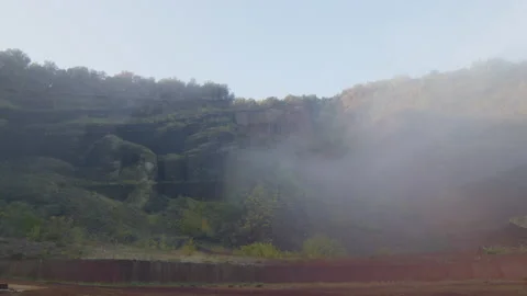 The mist falls on a landscape of red clay rock and green plants, in Spain Stock Footage 221274175