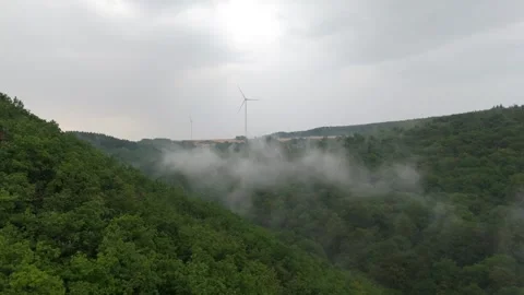 Mist filling forested valley below Hunsrück ridge wind farm Stockbeeldmateriaal 340367792