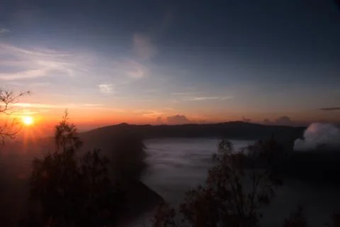 Mist hovering towards the active volcano Bromo in the morning during sunrise. Stock Photos
