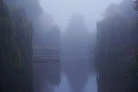 Mist on a lake at dawn with clouds reflected in the calm water. Foggy autumn Stock Photos