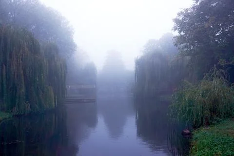 Mist on a lake at dawn with clouds reflected in the calm water. Foggy autumn Stock Photos