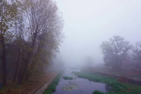 Mist on a lake at dawn with clouds reflected in the calm water. Foggy autumn Stock Photos