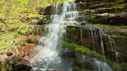 Mist rises from cascading water over mossy rocks. Tupavica Waterfall Stock Footage 335533604