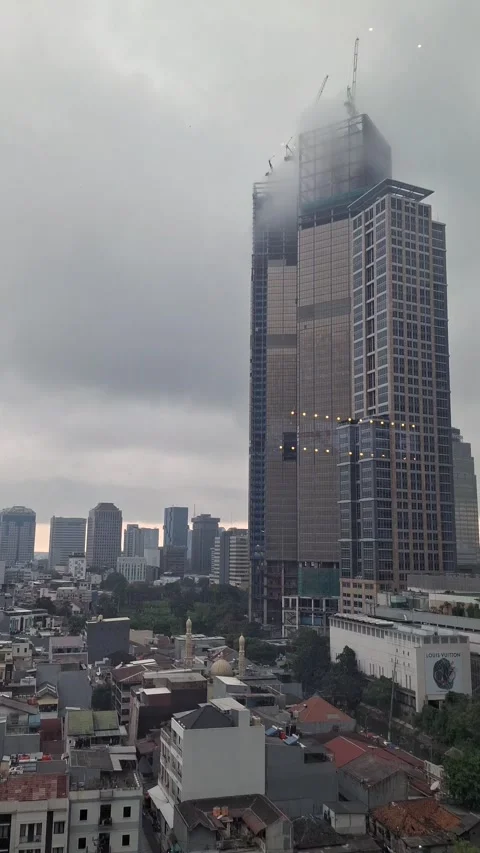 Mist surrounding the top of a modern high-rise building on a cloudy day. Video stock 336318541