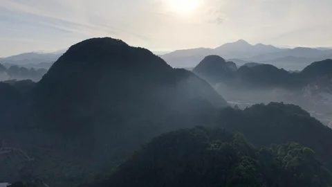 Mist wraps mountain peaks. Sunlight glints through thin clouds Stock Footage 340862003