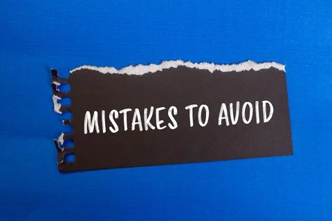 Mistakes to avoid message written on ripped black paper piece with blue backg 写真素材
