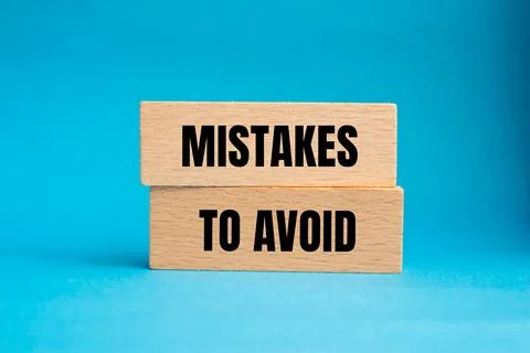 Mistakes to avoid message written on wooden blocks with blue background. Conc 写真素材