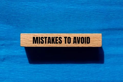 Mistakes to avoid message written on wooden block with blue background. Conce Foto stock