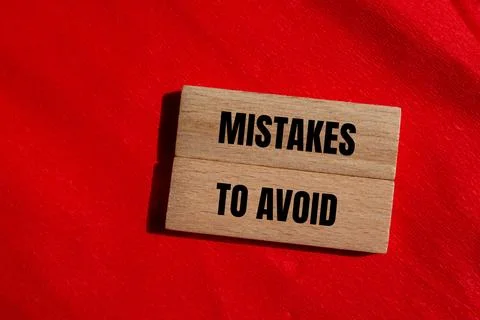 Mistakes to avoid message written on wooden blocks with red background. Conce Stock Photos