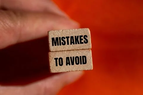 Mistakes to avoid message written on wooden blocks with orange background. Co Stockfoto's
