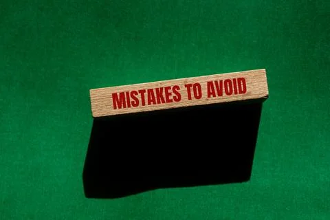 Mistakes to avoid message written on wooden block with green background. Conc Stockfoto's