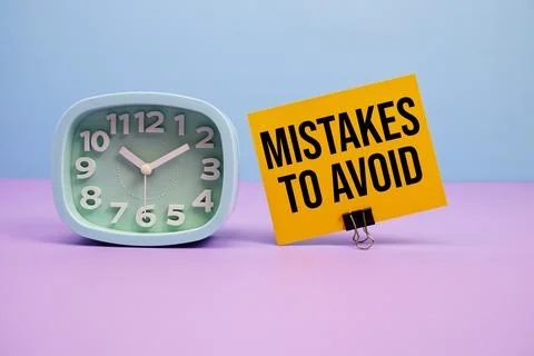 Mistakes To Avoid text and alarm clock on blue and purple background Stock Photos