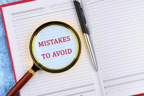 MISTAKES TO AVOID, text through a magnifying glass in an open business notebo Stockfoto's