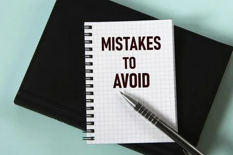 MISTAKES TO AVOID - words in a white notebook against the background of a bla Stock Photos