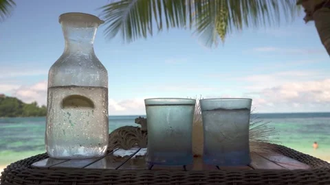 A misted jug of cold water and lemon sits on a beach Stock Footage 154807490
