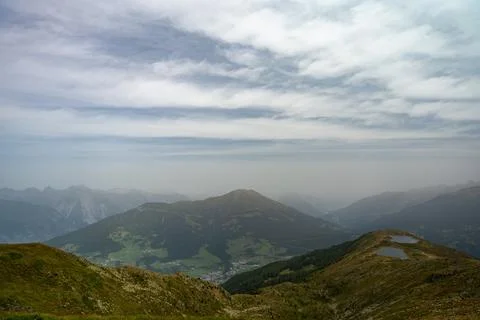Misty Alpine Mountain Landscape Overlooking Valley Lakes and Rolling Green .. Фото