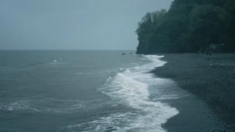 Misty beach view with gentle waves washing over pebbled shore under cloudy skies Stock Footage 274703477