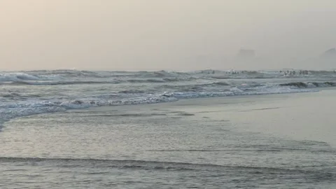 Misty city beach at dawn with rolling waves and foggy horizon and buildings Stock Footage 341543997