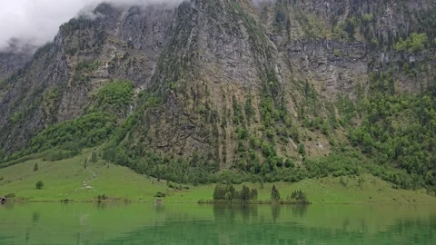 Misty cliffs reflecting in the crystal-clear waters of Lake Obersee in Berchtesg Stock Footage 309028479