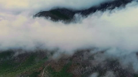 Misty clouds drift over rugged mountain peaks hyper lapse 스톡 동영상 332498840