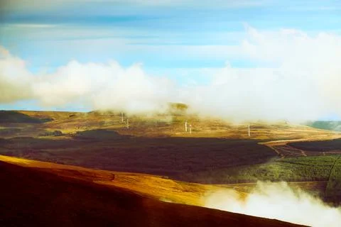 Misty clouds drift over vast brown hills and distant green valleys 写真素材
