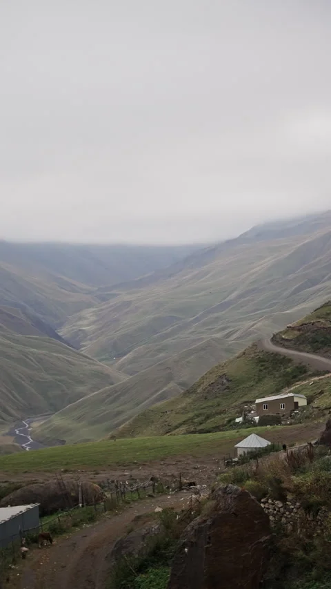 Misty clouds drifting over serpentine mountain road, unveiling lush valley Stock Footage 297611256