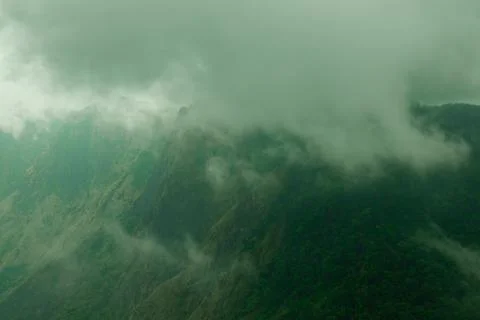 Misty clouds passing on top of the mountains or hills. Greenery mountains o.. Stock Photos