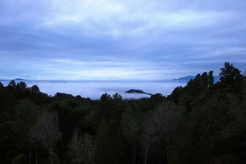 A misty, cloudy sky with a mountain in the background Stock Photos