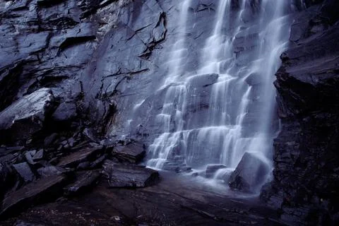 Misty, cool water flows down jagged rock face in North Carolina Stock Photos