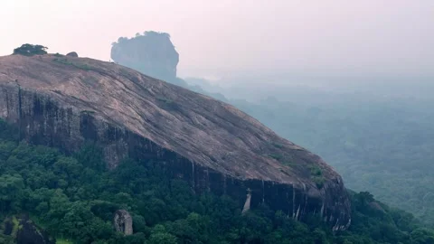 Misty morning view of Pidurangala Rock, Sri Lanka, with Sigiriya Rock faintly Stock Footage 305024341