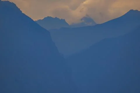 Misty mountain range under a cloudy sky at dusk Stock Photos