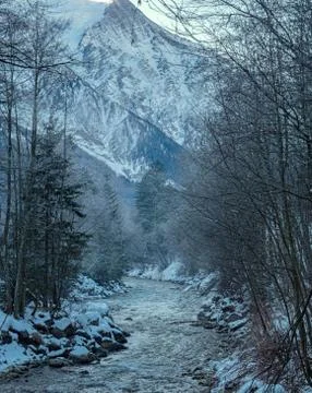 A misty mountain stream flows through a snowy landscape Stock Photos