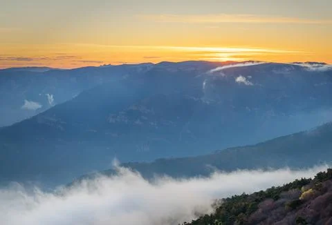 Misty mountains and clouds create a magical atmosphere against the dawn light Stock Photos