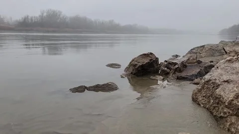 Misty River Morning with Foreground Rocks and Calm Water Stock Footage 330310863