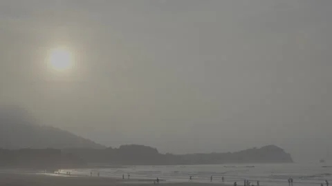 Misty sunrise beach with bright sun over ocean and distant mountains. Stock Footage 336797296