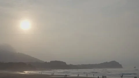 Misty sunrise beach with bright sun over ocean and distant mountains. Stock Footage 336797306