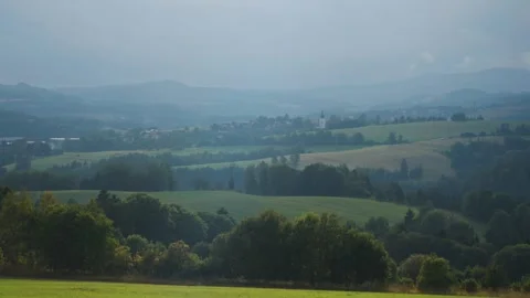 A misty valley overlooking a distant village as fog rolls through the 動画素材 285152087