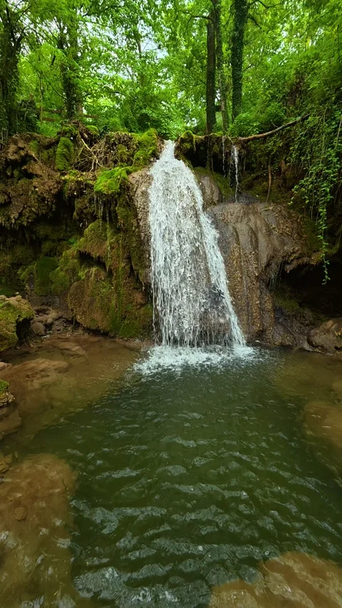 Misty waterfall cascades down into pool. Sokobanja, Serbia. Vertical Stock Footage 335954253