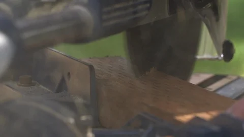 Miter Saw Cuts Through Piece of Wood Outside With Sawdust and Green Grass Vidéo 102873707