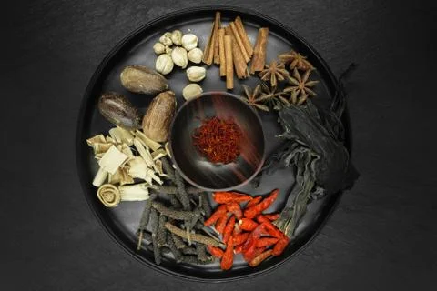 Mix composition of various exotic dried spices in black round bowl on black s Stock Photos