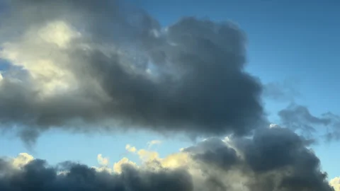 A mix of dark ominous storm clouds move across a blue sky Stock Footage 330591915