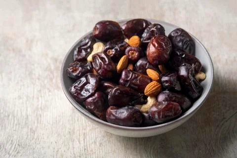 Mix of dates and nuts in plate on a white wood background .healthy food Stock Photos