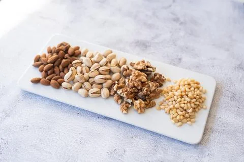 Mix of different nuts on a white plate. Stock Photos