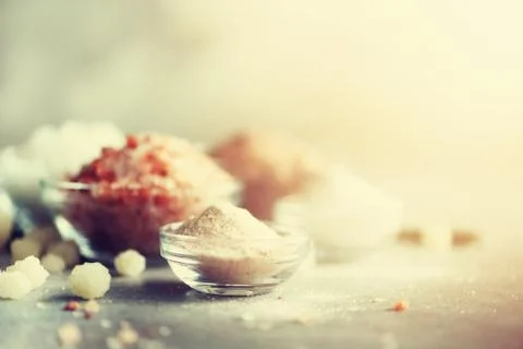 Mix of different salt types on grey concrete background. Sea salts, black and Stock Photos